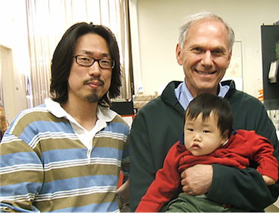 UCLAで研究をされていた当時の金さん。マイケル・グルンスタイン博士に抱っこされているのが金さんの息子さんです。　写真提供：アクプランタ株式会社
